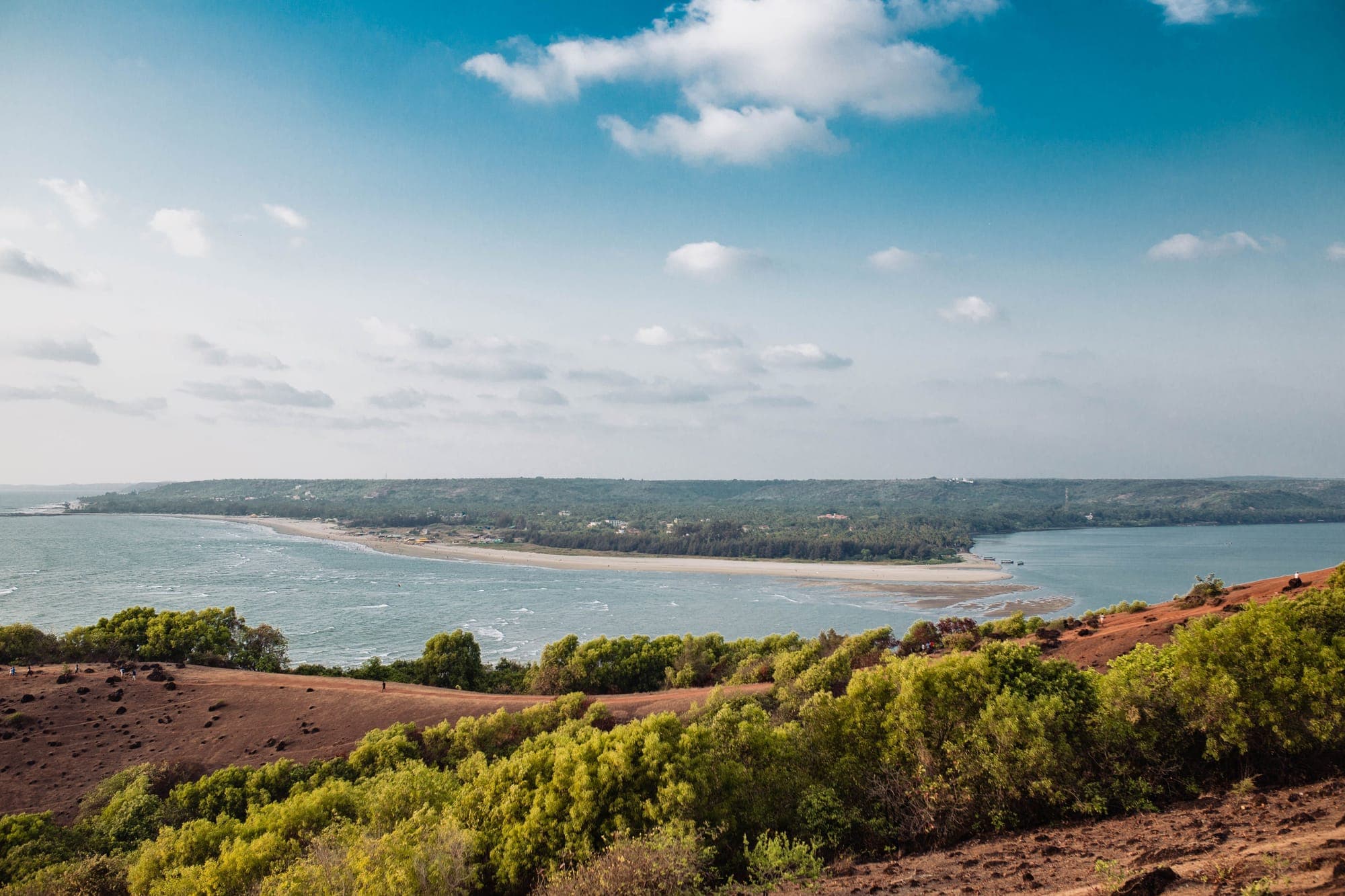 Aerial view of a curving sandy bay backed by forested hills