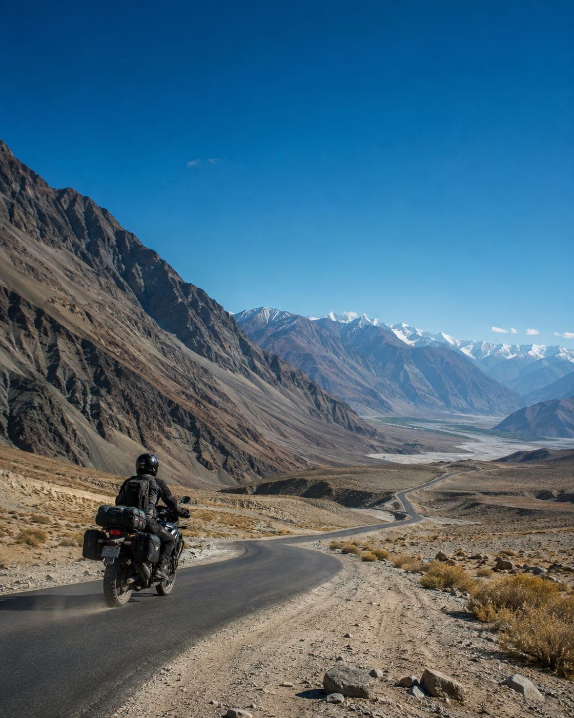 Motorcyclist riding a winding road through the Ladakh mountains