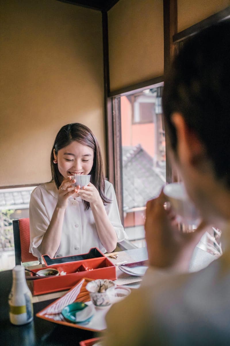 Woman smiling while holding a warm drink by a window